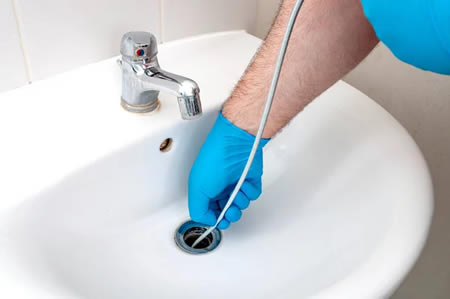 Drain snake cable placed beside a bathroom sink drain